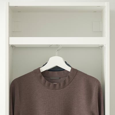 White closet with KOMPLEMENT rail, hanging a dark patterned shirt.