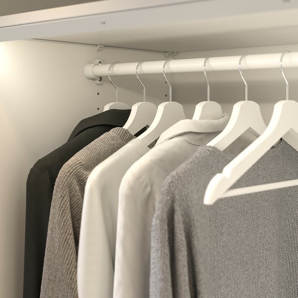 Closet with black and white clothes on hangers, organized on a white rail.