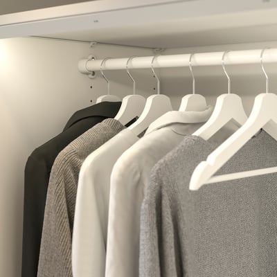 White KOMPLEMENT rail with hangers and clothes in black, grey, white.
