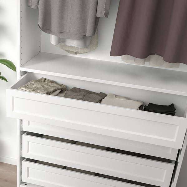 White wardrobe with slid open drawer revealing neatly folded clothes, part of modern storage solution.