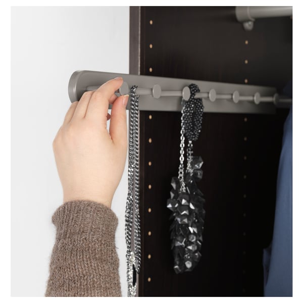 A hand adjusts a grey multi-use hanger with hooks for accessories in a wardrobe.
