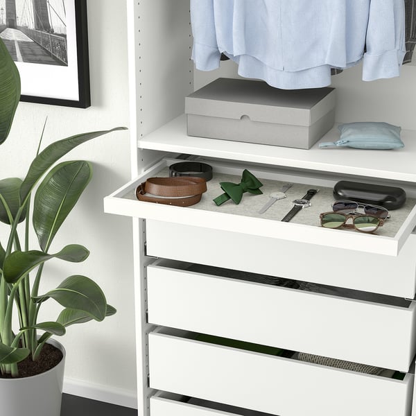 White wardrobe with accessories tray, drawers, and plant beside.