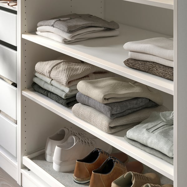 White KOMPLEMENT wardrobe shelf with neatly folded grey sweaters and boots.