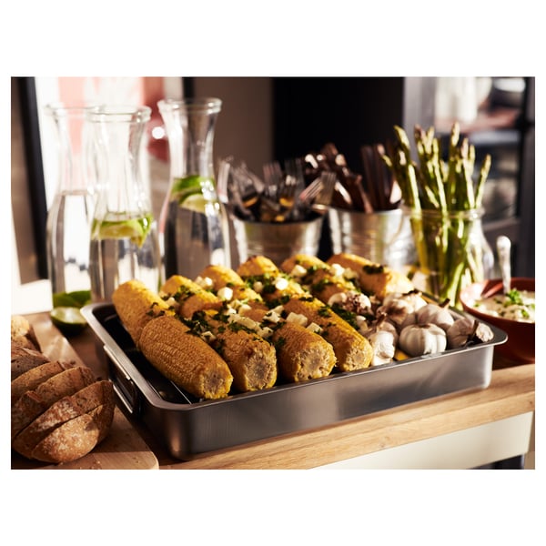 Metal cooking tray holds cooked corn, bread, and veggies; perfect for serving meals.