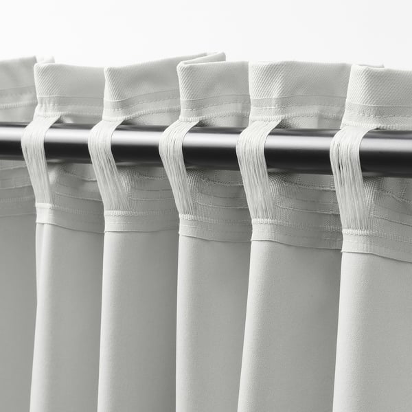 Close-up of white KORGMOTT block-out curtains, showing dense fabric texture and multi-way hanging tabs.