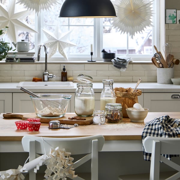Modern kitchen counter with KORKEN jars for baking, featuring ingredients, utensils, and festive decorations.