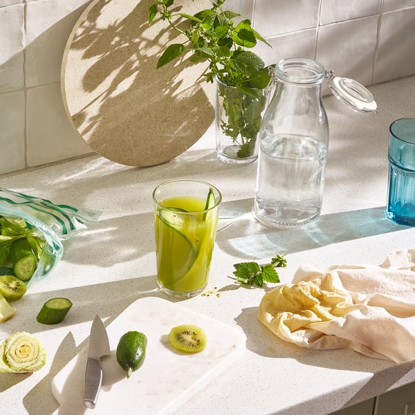 Kitchen counter with KORKEN jars, mint water, juice, kiwi, lime prep.
