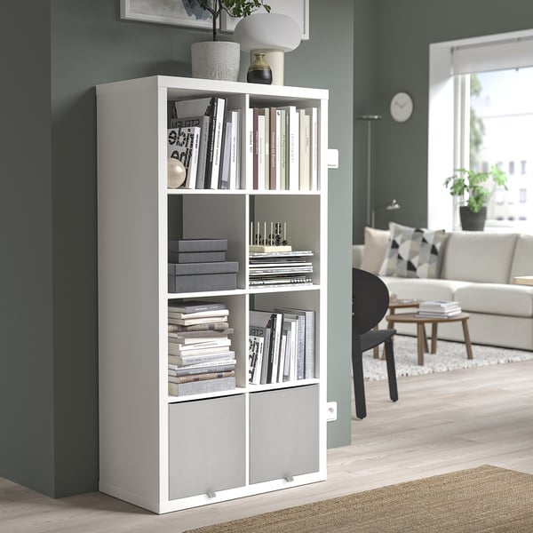 White KOSINGEN storage box in kallax unit, holding books & decor, fits neatly in corner, blending with modern room decor.