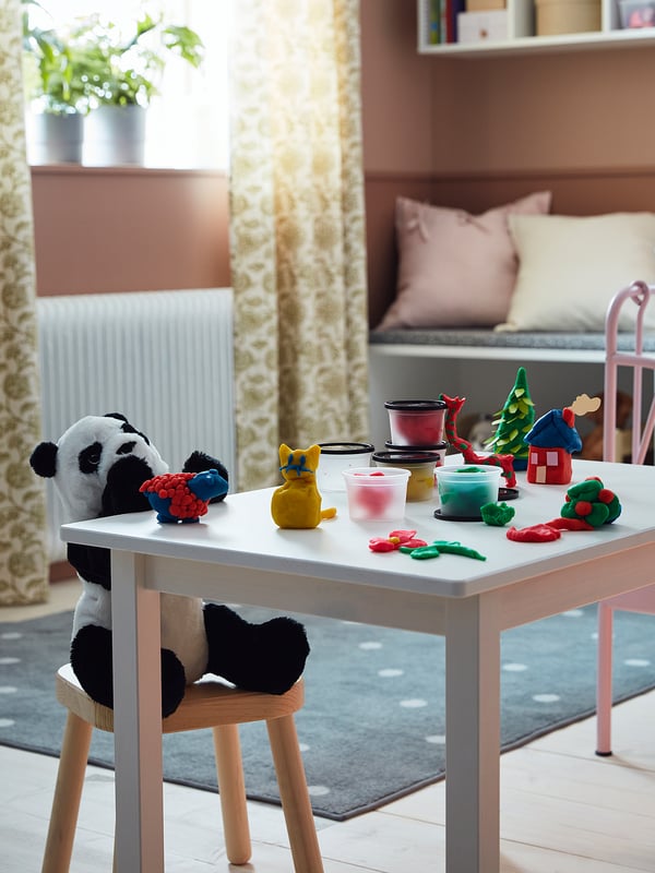 Childs play table with wooden chairs; colourful plastic toys and a black and white stuffed panda.