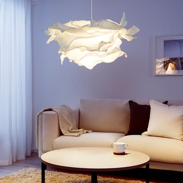Pendant lamp with rippled design, above sofa, emitting soft light.