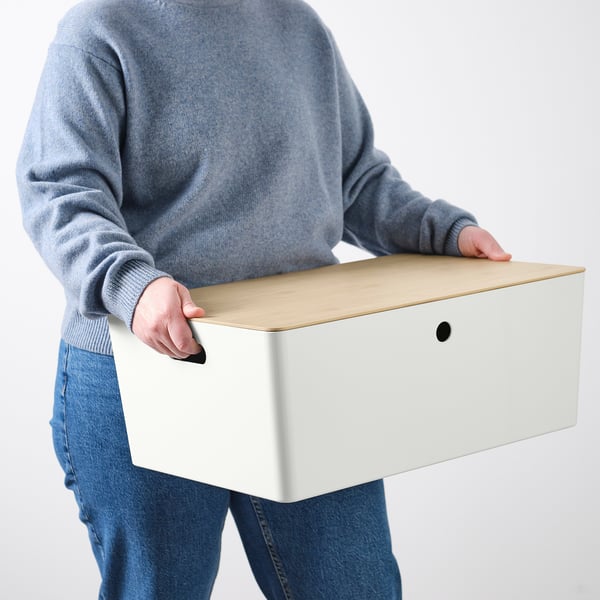 Person carrying large storage box with lid and handle. Ideal for family games or hobbies, fits bestå shelves.