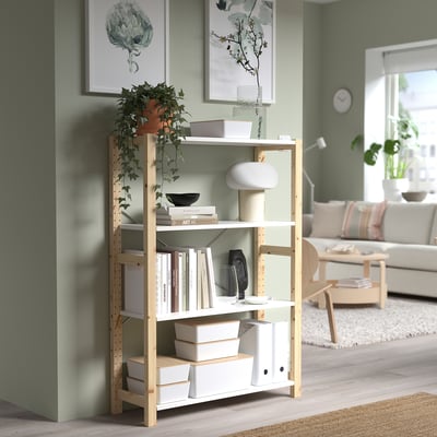 Light wooden shelf, KUGGIS white boxes, green plant, living room setting. Small KUGGIS box stacked on lower shelf.