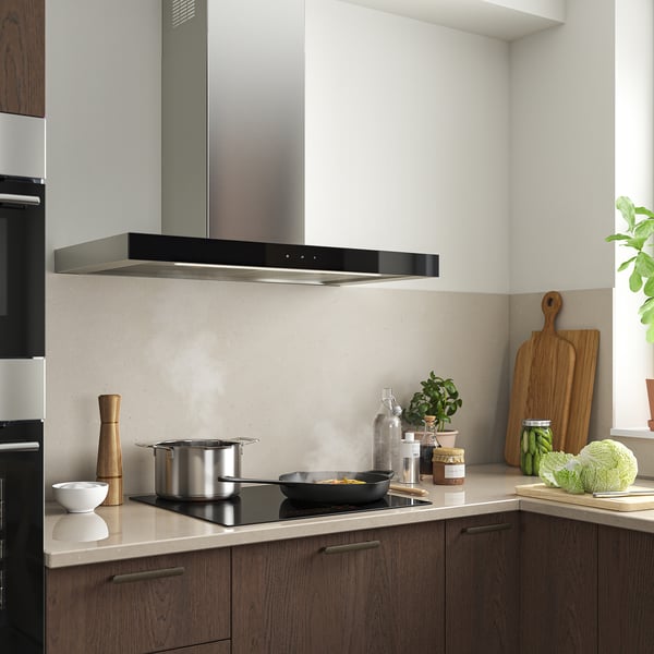Modern kitchen with KULINARISK black stainless steel range hood. It has touch controls, led lights, and extracts fumes effectively.