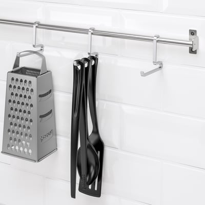 Silver rail with hooks; hangs cheese grater and black utensils.