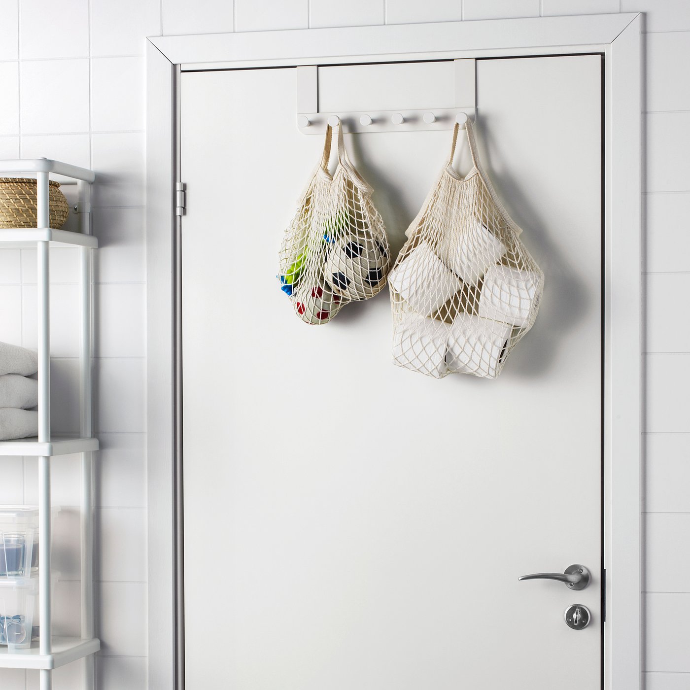 KUNGSFORS net bags hang on a door hook, storing colorful fruits and veggies, larger than cups on a nearby shelf.