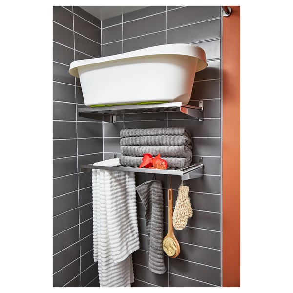 Stainless steel wall shelf with white tub, grey towels, red brush, hanging sponge and scrubber, modern bathroom storage.