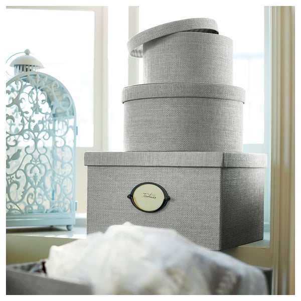 Stack of grey KVARNVIK storage boxes near a decorative blue lantern.
