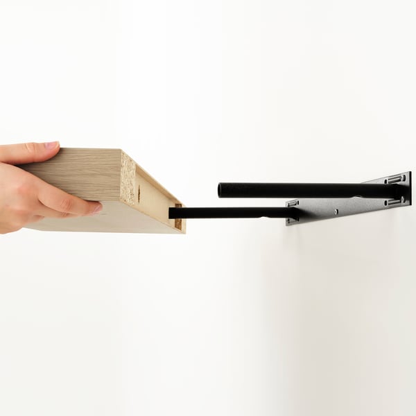 Person holding modern wooden wall shelf with minimalist brackets.