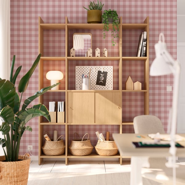 Wooden lådda storage unit with shelves and cabinets against chequered wall, holding plants, books, and decor.
