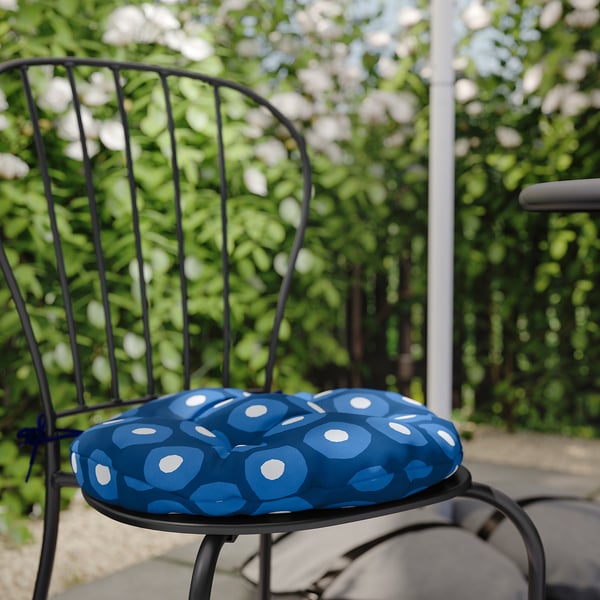 Black metal chair with blue circular patterned cushion outdoors.