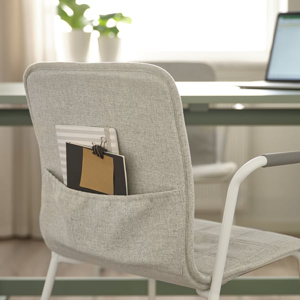 A light grey office chair, LÄKTARE, with a notepad in its pocket. It has lumbar support for comfort and ease of use.