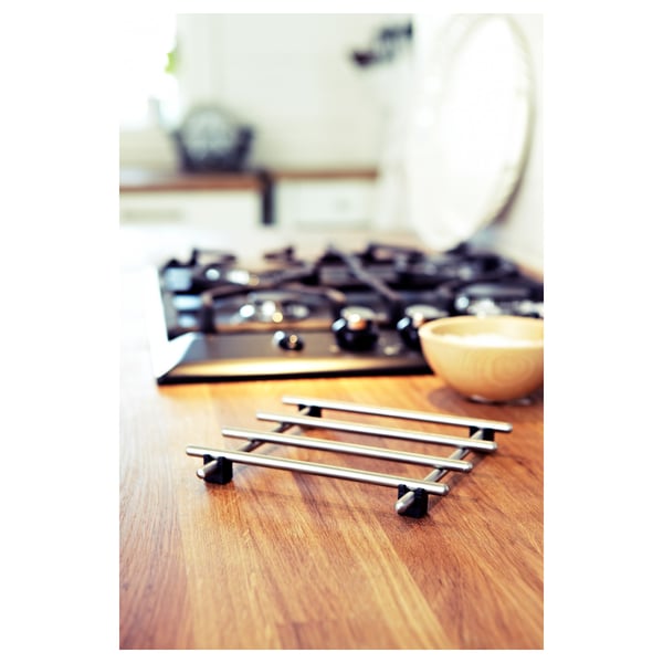 Kitchen scene: black stove, wooden countertop, metallic grid trivet, yellow bowl.