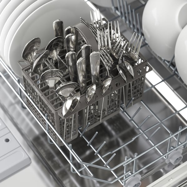 An open dishwasher with a cutlery basket filled with spoons, forks, and knives, ready for washing.