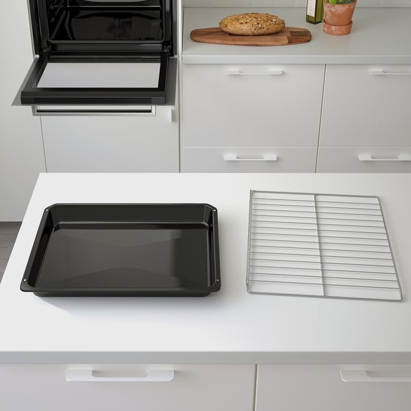 Black baking tray and wire rack on white kitchen counter beside built-in oven.
