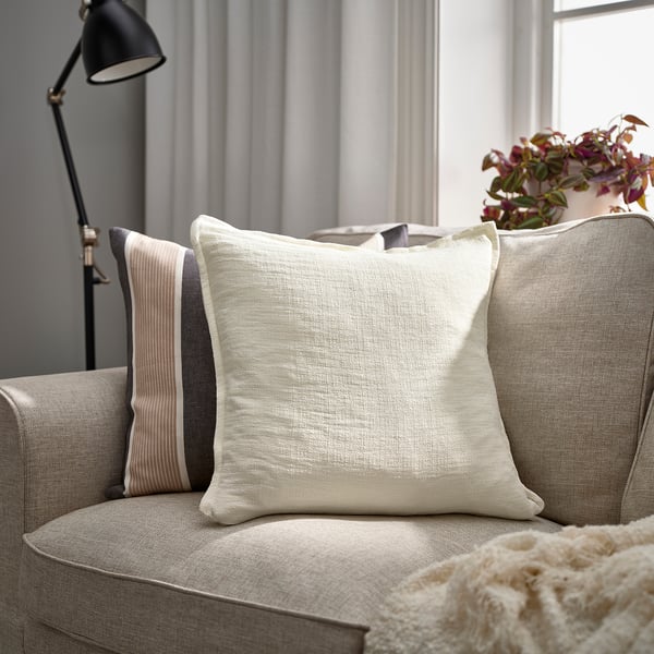 Cosy living room with LAGERPOPPEL cushions, grey sofa, throw pillow, and blanket. Enhanced with lamp and plant.