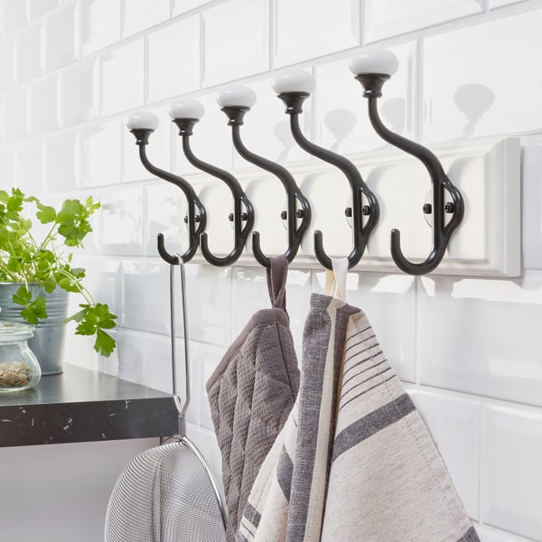 Black wall rack with five double hooks holding towels, offering ample hanging space in a kitchen setting.