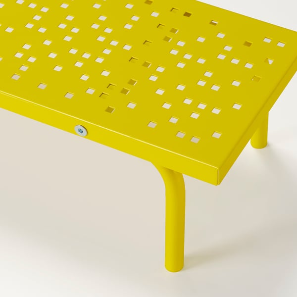 Bright yellow metal stand with perforated design, supportive legs, likely used for ergonomic monitor placement.