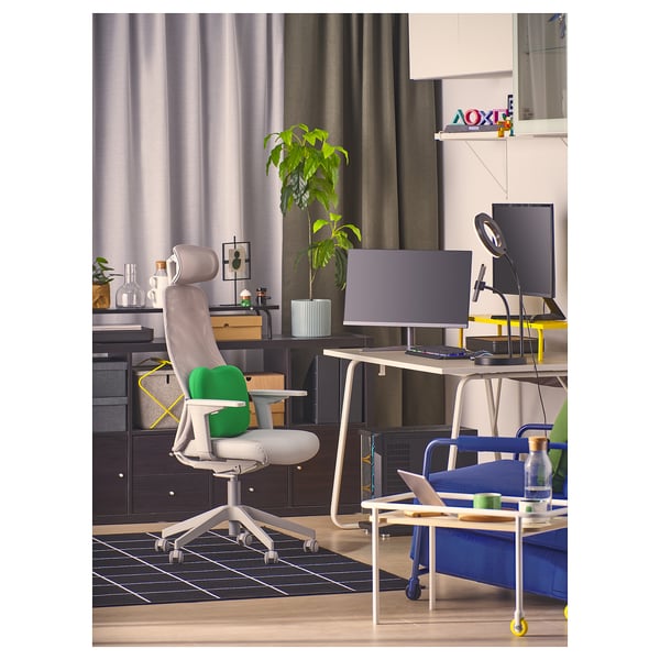 Modern home office with LÅNESPELARE stand, grey-green chair, desk, plants, books, blue sofa.