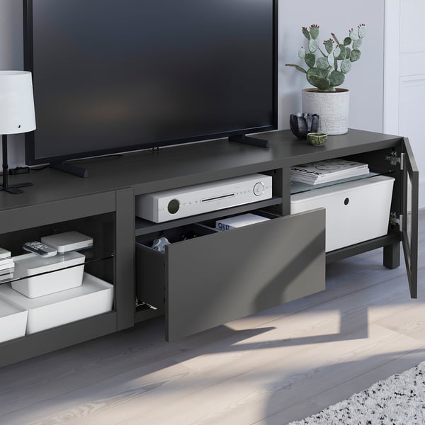 Modern tv stand with multiple storage drawers, holding electronics and decor.