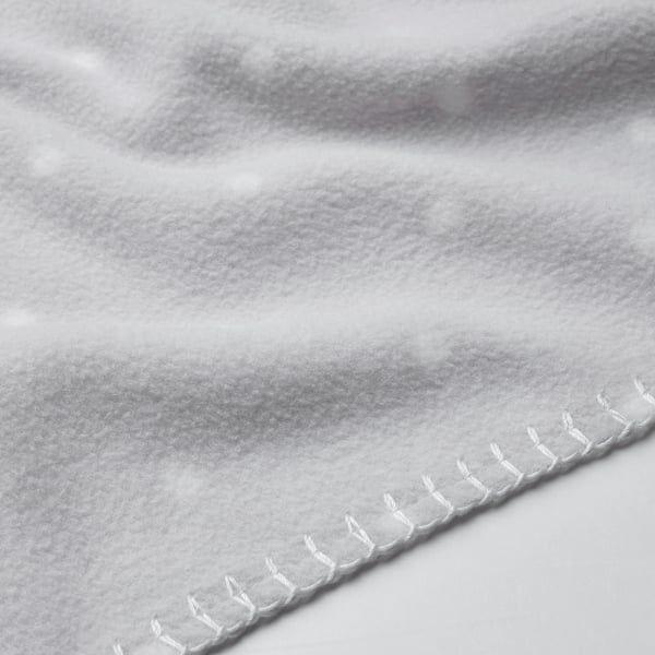 Soft, textured close-up of a plush blanket with visible white stitching, highlighting its smooth and durable material.