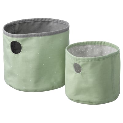 Two pastel green fabric storage bins, one larger, one smaller, with grey polka dot interiors and small handles.