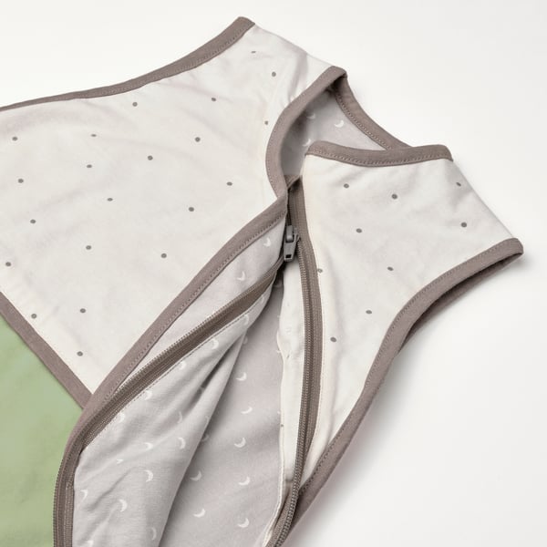 Soft, neutral-colored baby sleep bag with cute polka dots, zipped halfway, showcasing high-quality stitching and comfy fabric.