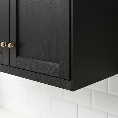 Black kitchen cabinet with gold handles, fitted above white tiles.