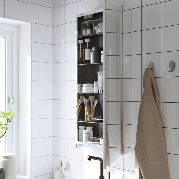A mirrored bathroom cabinet hangs towels, with shelves holding toiletries, making efficient use of space and enhancing lighting.