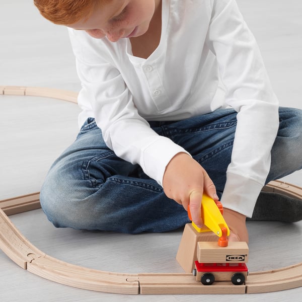 Child plays with LILLABO train, using crane with magnet to lift container, developing motor skills.