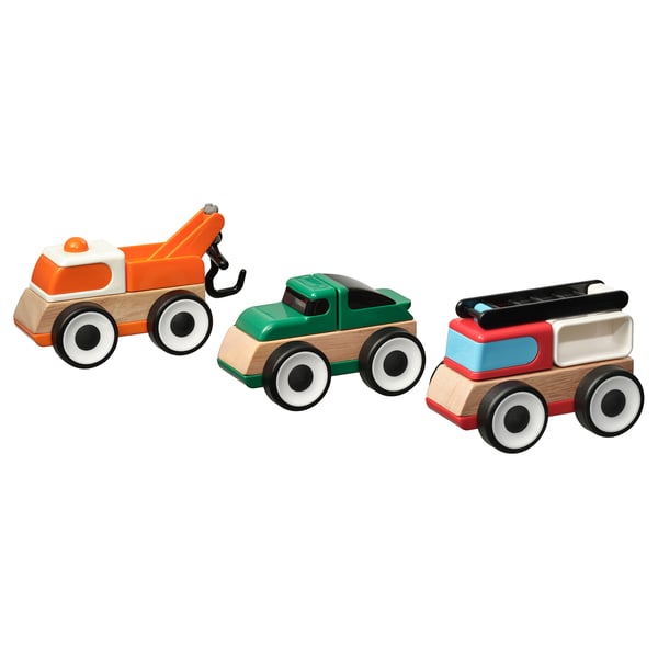 Three colourful wooden toy trucks in orange, green, and red/blue, each with large white wheels and simple designs, arranged side by side.