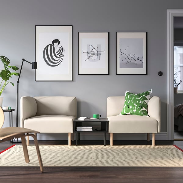 Modern living room with grey walls, lillehms, plant, art, and patterned rug.