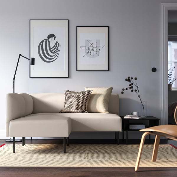 Modern living room with LILLEHEM sofa, abstract art, dark table, geometric rug, stylish lamp, plant, and chair, cosy and contemporary.