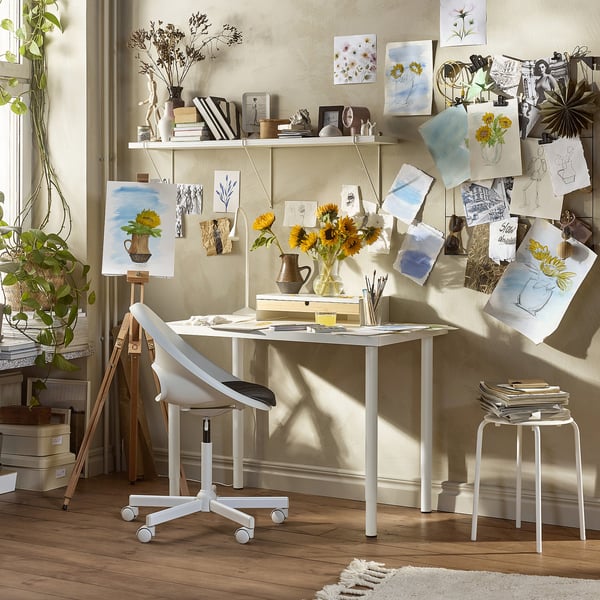 Art studio with table, chair, sketches, and sunflowers.