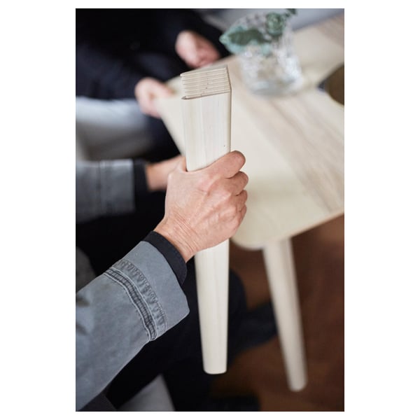 Hand grips sturdy, light wooden chair, showcasing quality craftsmanship in dining set.