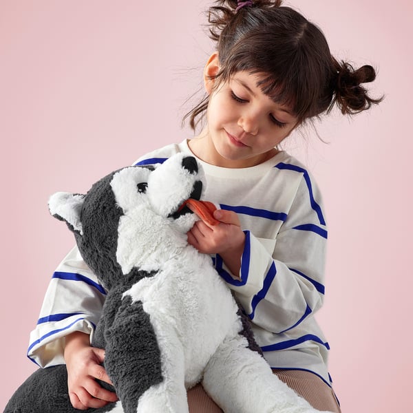 Girl hugs blue-eyed stuffed toy in stripes.