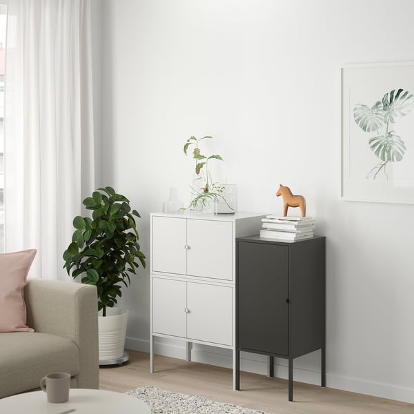 Minimalist living space with white LIXHULT cabinet, dark wooden horse, green plant, and light-colored sofa.