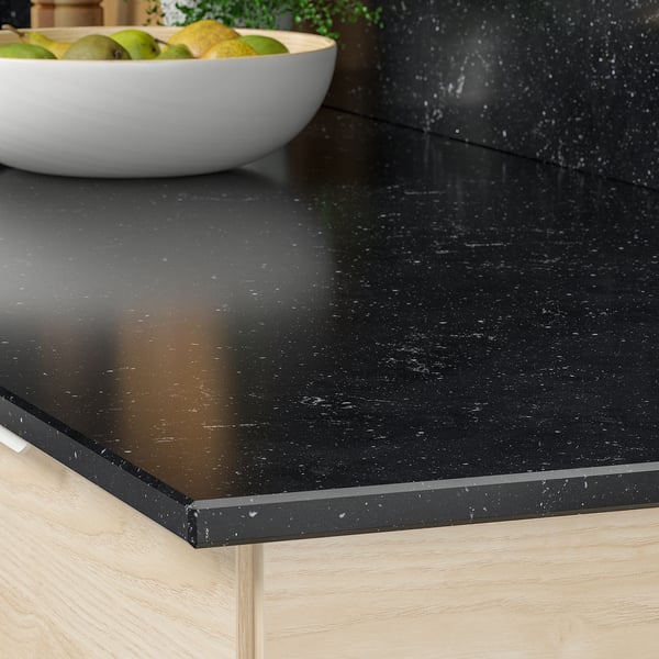 Kitchen countertop with bowl of fruit. Durable, stain-resistant, recycled glass surface.