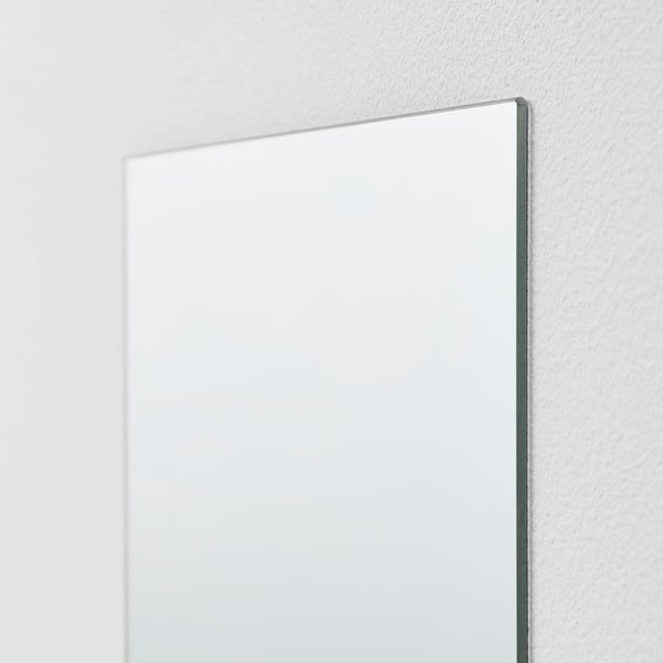 Large rectangular mirror with thin silver frame, mounted on a white wall.