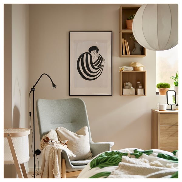 Cosy bedroom corner with a green armchair, wooden shelves, and modern art print.