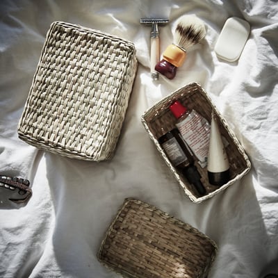 Woven seagrass baskets with shaving items on cloth.
